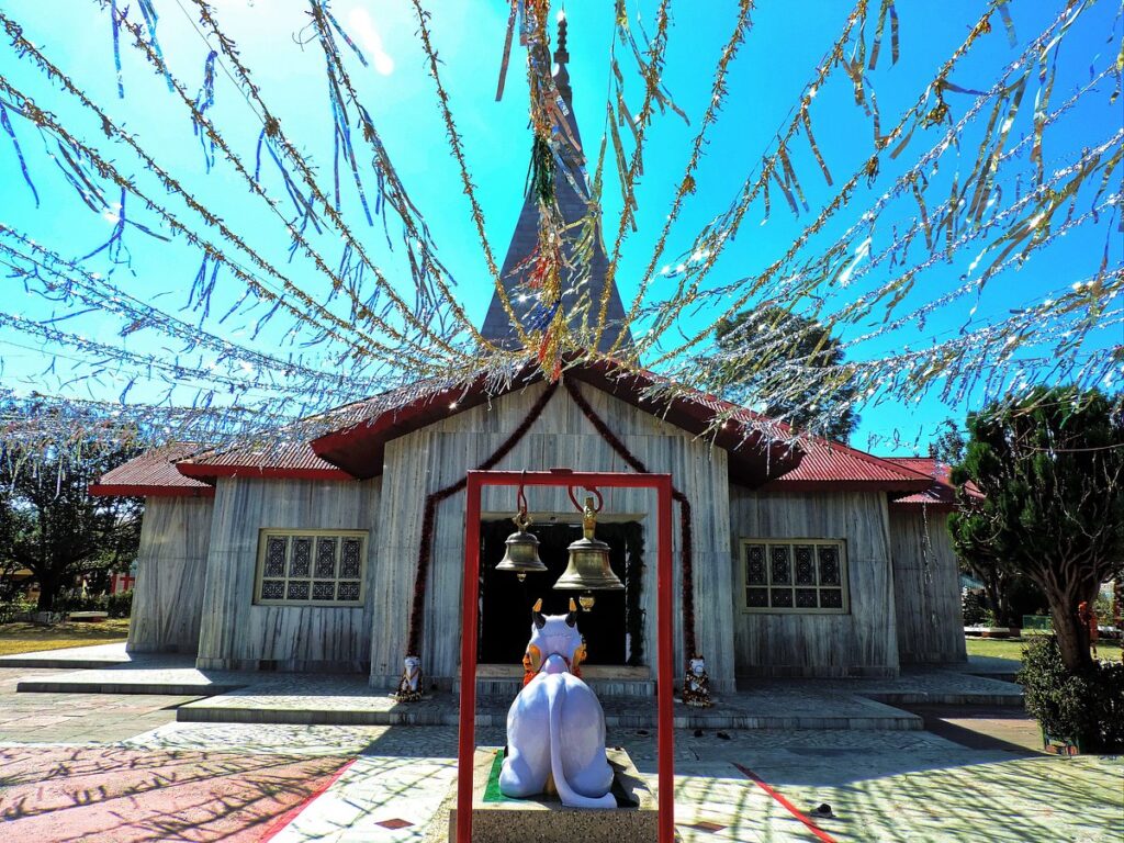 Hedakhan Ashram – A Spiritual Retreat in the Kumaon Hills Haidakhan Ashram Temple, nestled in the serene hills of Uttarakhand, radiates peace and spiritual energy. Decorated with colorful streamers under the clear blue sky, this sacred temple offers a tranquil atmosphere for meditation, prayer, and self-discovery. The beautifully crafted structure, temple bells, and divine surroundings make it a cherished destination for devotees and travelers seeking inner peace and Himalayan spirituality.